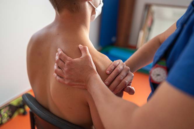 Un masseur-kinésithérapeute palpe l&#039;épaule de son patient