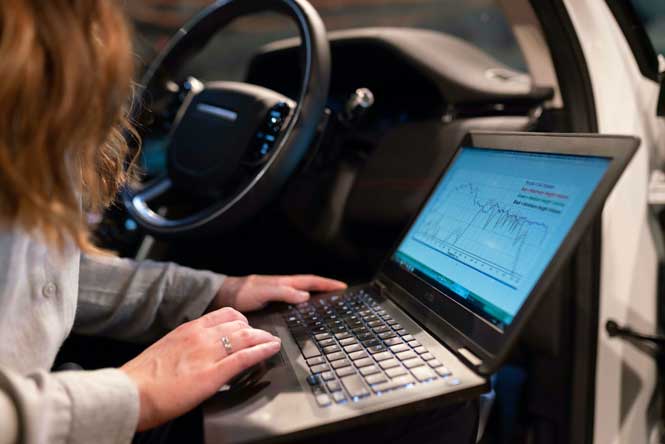 Ingénieure faisant des tests dans une voiture avec son ordinateur portable