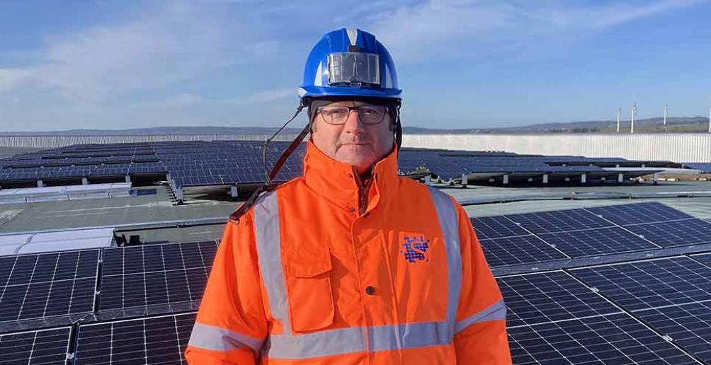 Portrait de Jean-Claude Morel devant une étendue de panneaux photovoltaïques