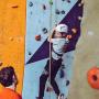 Jeune sur un mur d&#039;escalade encadré par un éducateur sportif