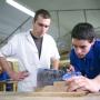 Un jeune est en train de scier une pièce de bois