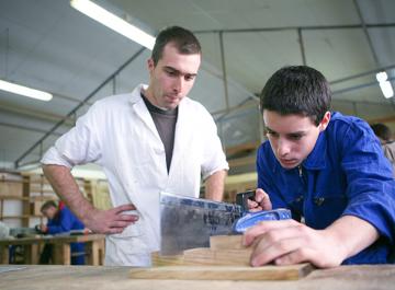 Un jeune est en train de scier une pièce de bois 