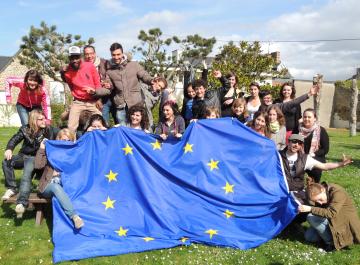 Des personnes posent derrière un drapeau européen