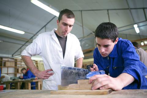 Un jeune est en train de scier une pièce de bois 