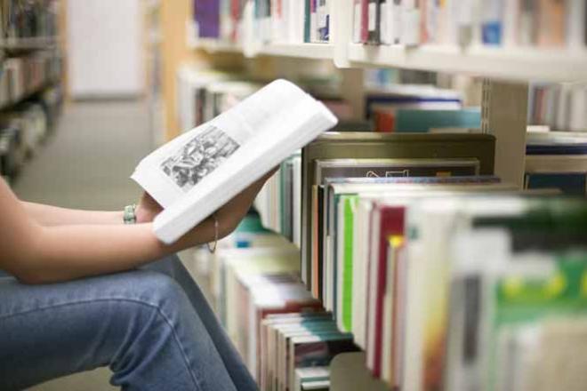 Etudiante lisant un livre dans une bibliothèque