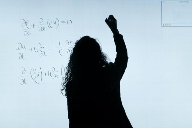 Une femme note des équations sur un panneau lumineux