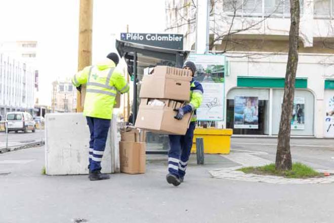 Deux agents de propreté urbaine ramassent des cartons dans une rue