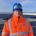 Portrait de Jean-Claude Morel devant une étendue de panneaux photovoltaïques